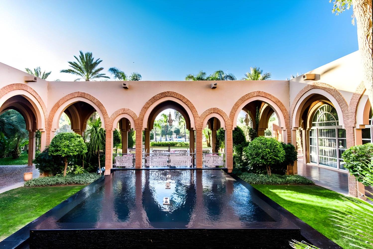 Architecture élégante de l'Ôclub Zen Barceló Palmeraie avec des arches et un bassin d'eau.