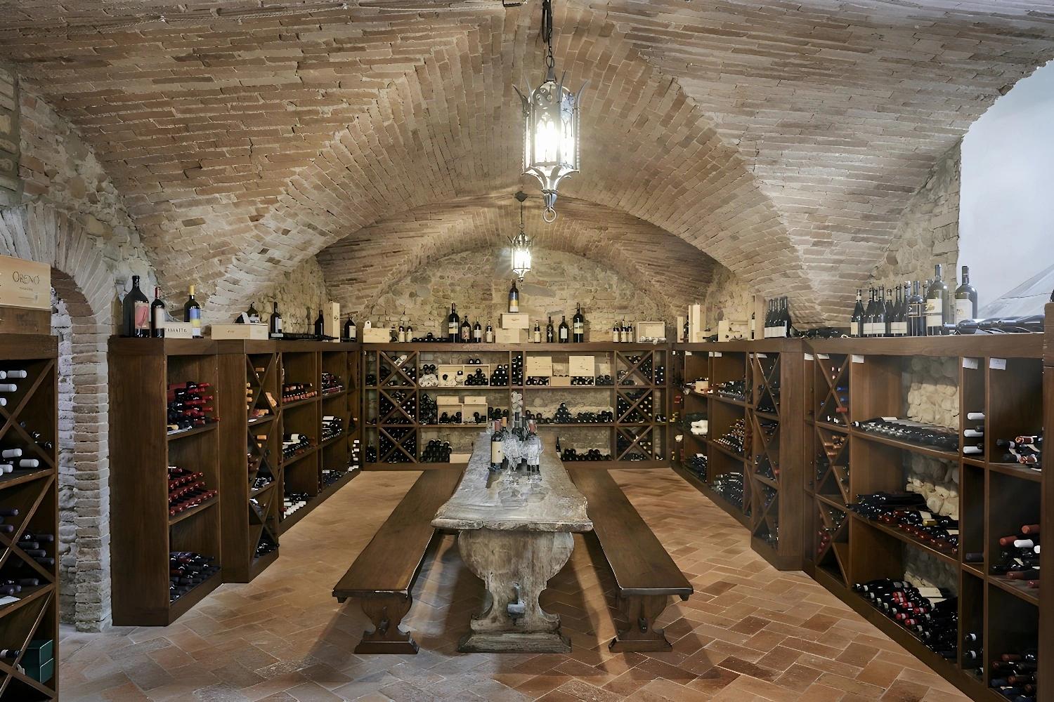 Cave à vin du COMO Castello del Nero avec des bouteilles et des étagères en bois