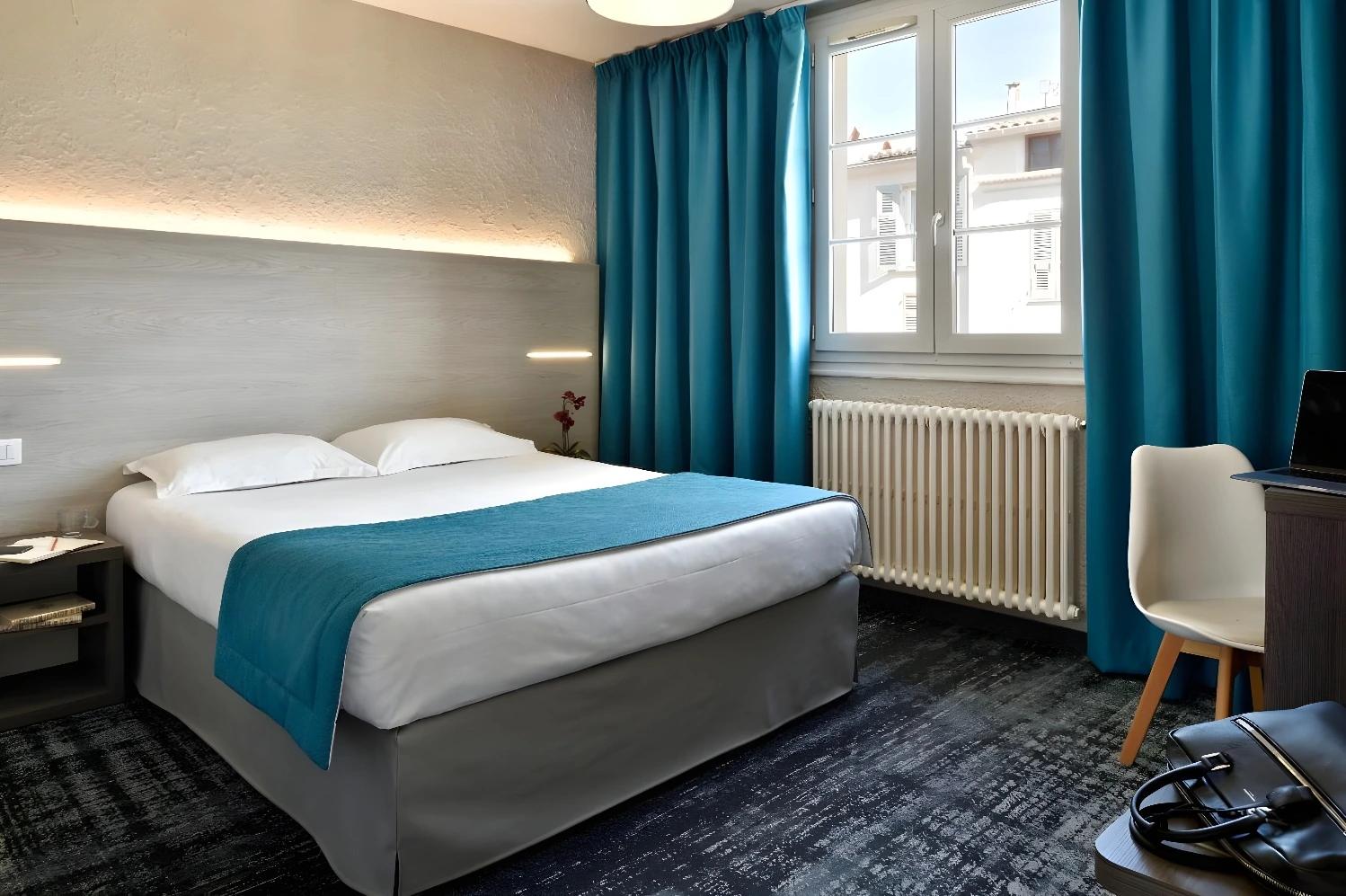 Chambre double moderne à l'Hotel Fesch & Spa avec rideaux bleus.