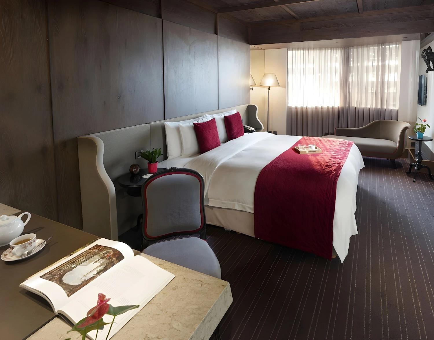 Chambre double confortable au Palais De Chine Hotel avec des accents rouges et un éclairage doux.