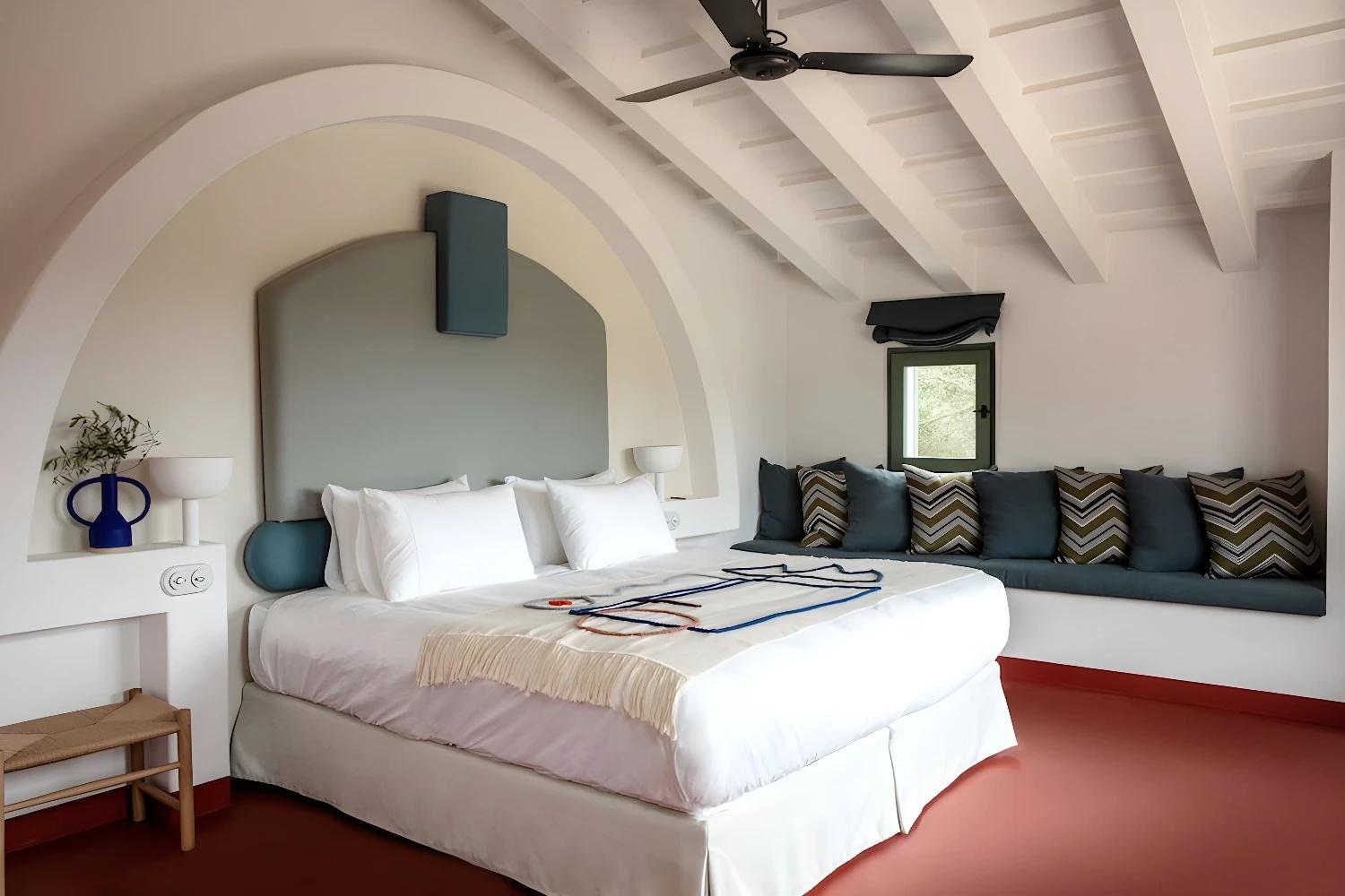 Chambre élégante à Menorca Experimental avec un grand lit et des coussins colorés.
