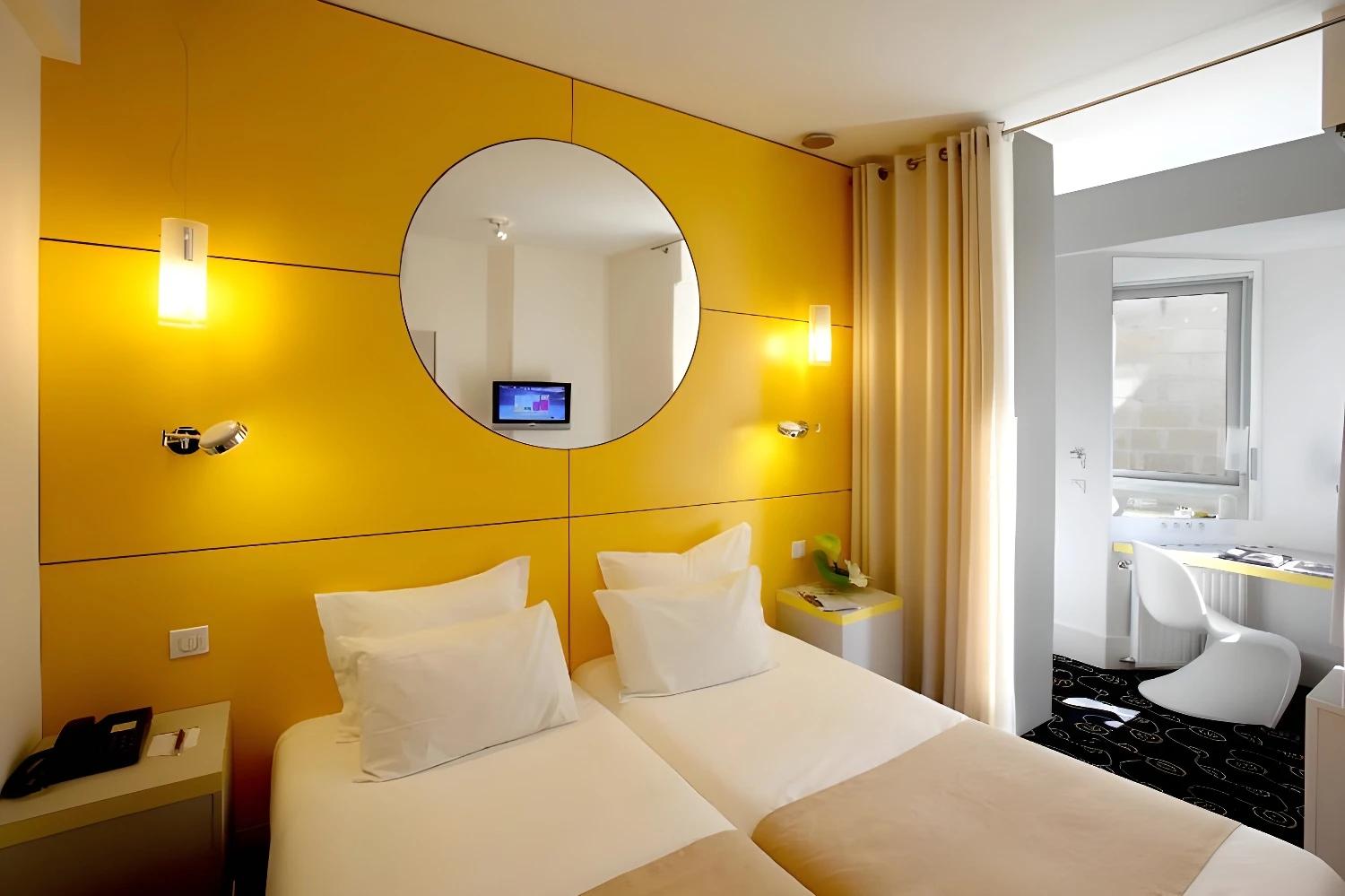 Chambre moderne et colorée du BW Grand Hôtel Français avec deux lits simples.