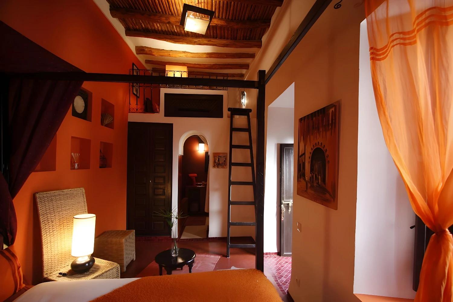 Chambre chaleureuse du Riad Boussa avec des murs orange et un lit confortable.