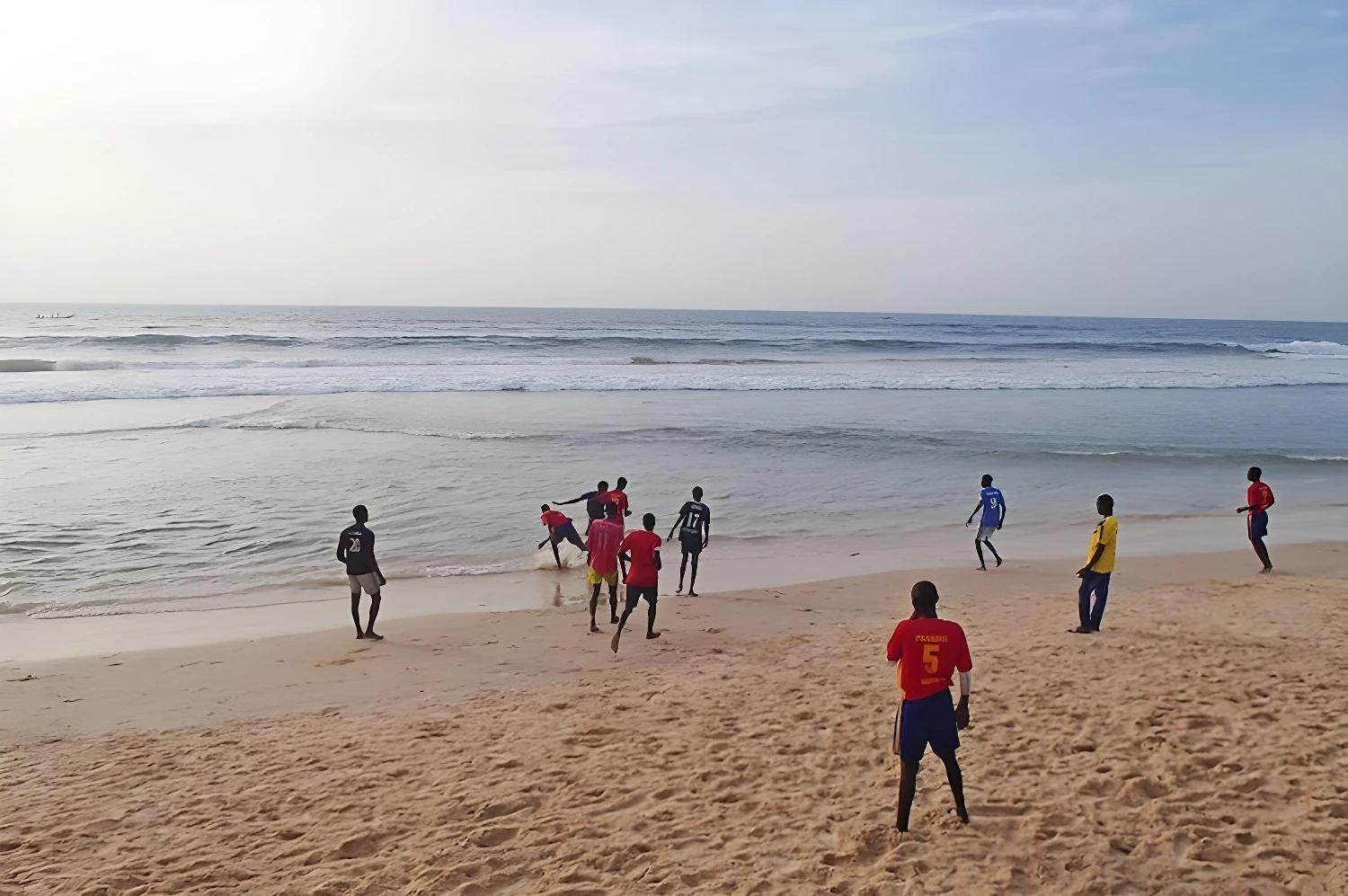 Jeunes jouant au football sur la plage, symbolisant le produit "Entre océan et savane".