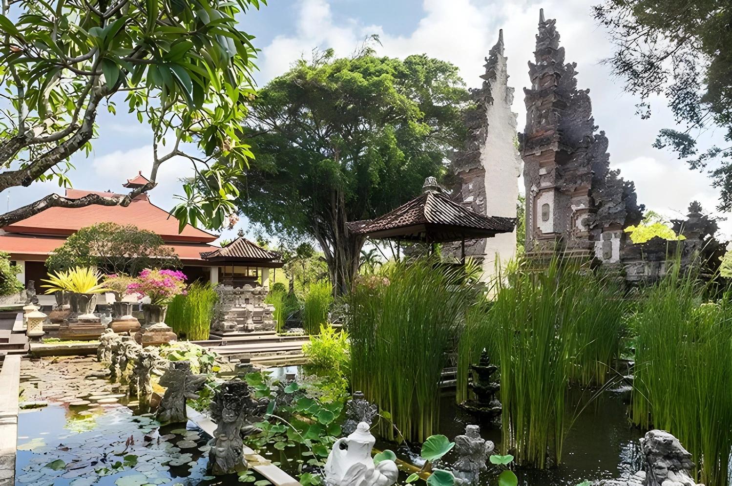 Jardin traditionnel balinais au Nusa Dua Beach Hotel & Spa avec étang et sculptures.