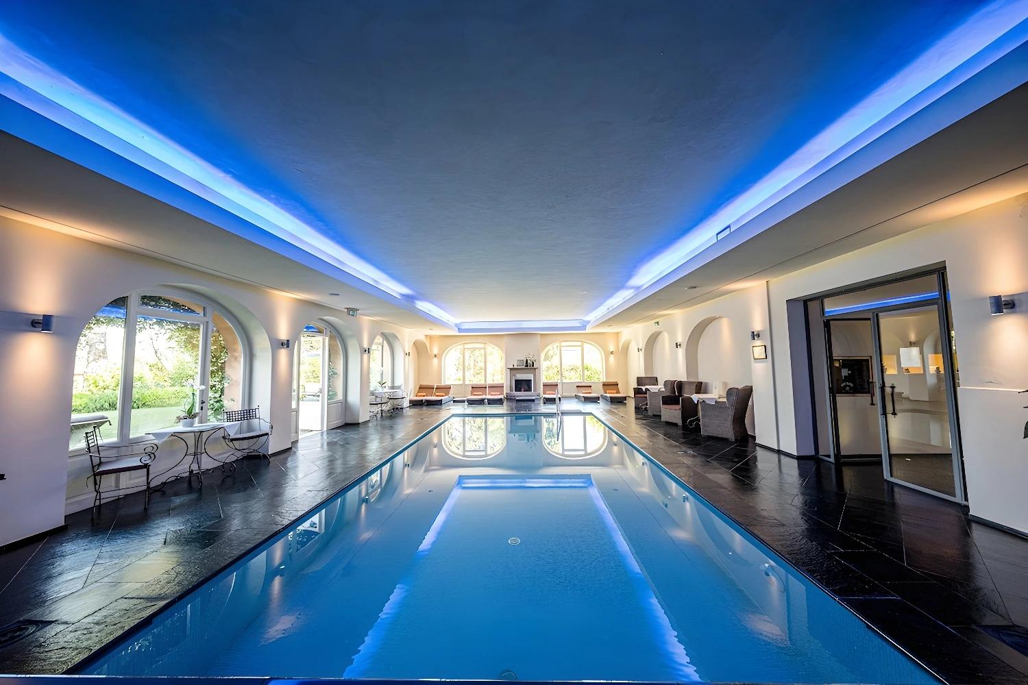 Piscine intérieure moderne de L'Andana Resort avec éclairage bleu.