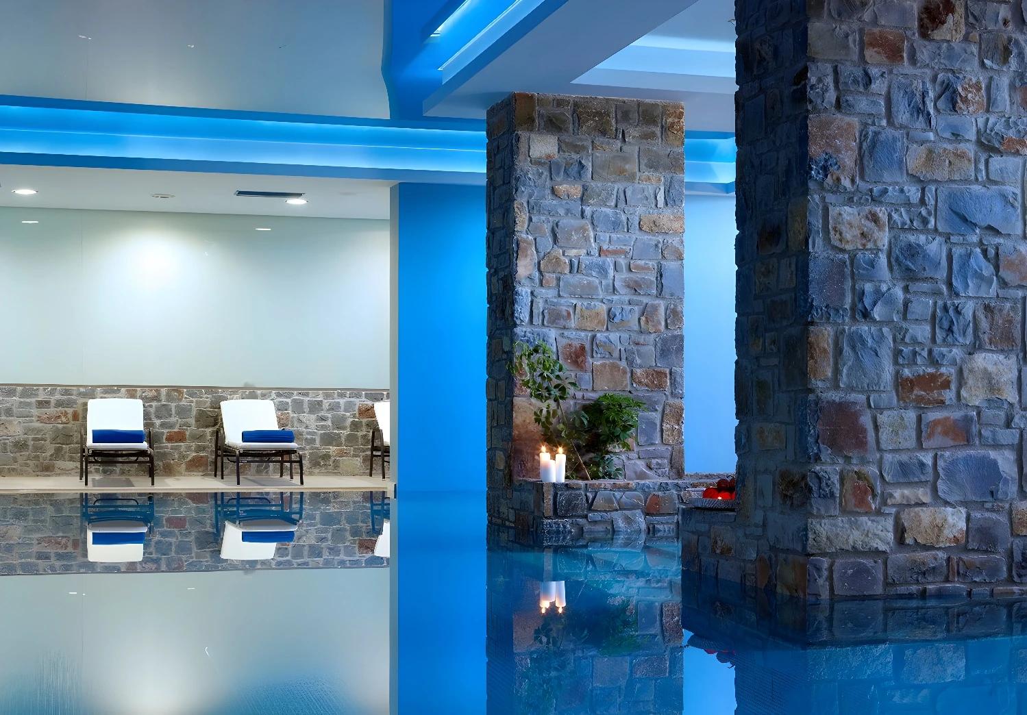 Vue de la piscine intérieure du Filion Suites Resort & Spa avec des colonnes en pierre.