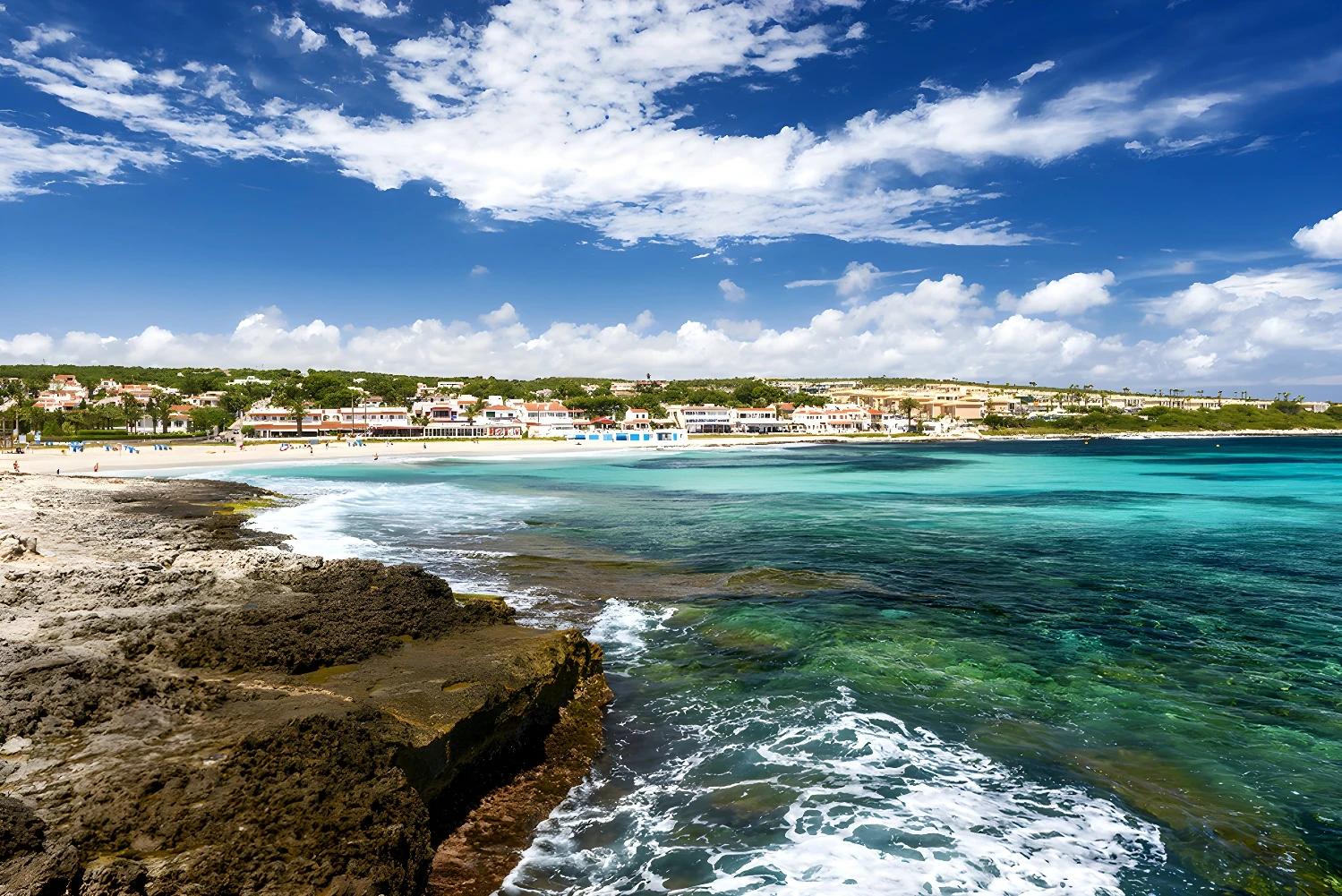 Plage magnifique près de l'Ôclub Experience Occidental Minorque avec des eaux turquoise et un ciel bleu.