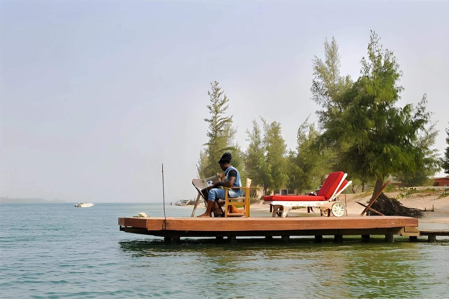 Personne assise sur un ponton au bord de l'eau à Saint-Louis.