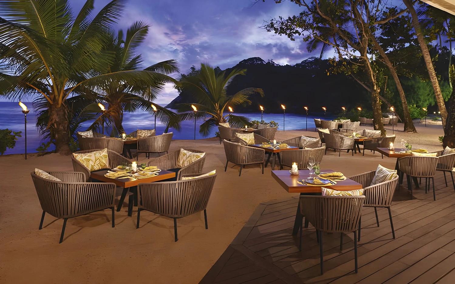 Restaurant en bord de mer à l'Avani Seychelles Barbarons Resort & Spa au coucher du soleil.