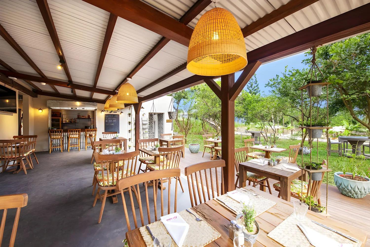 Restaurant en plein air de Kaz'alala avec tables en bois et décoration chaleureuse.