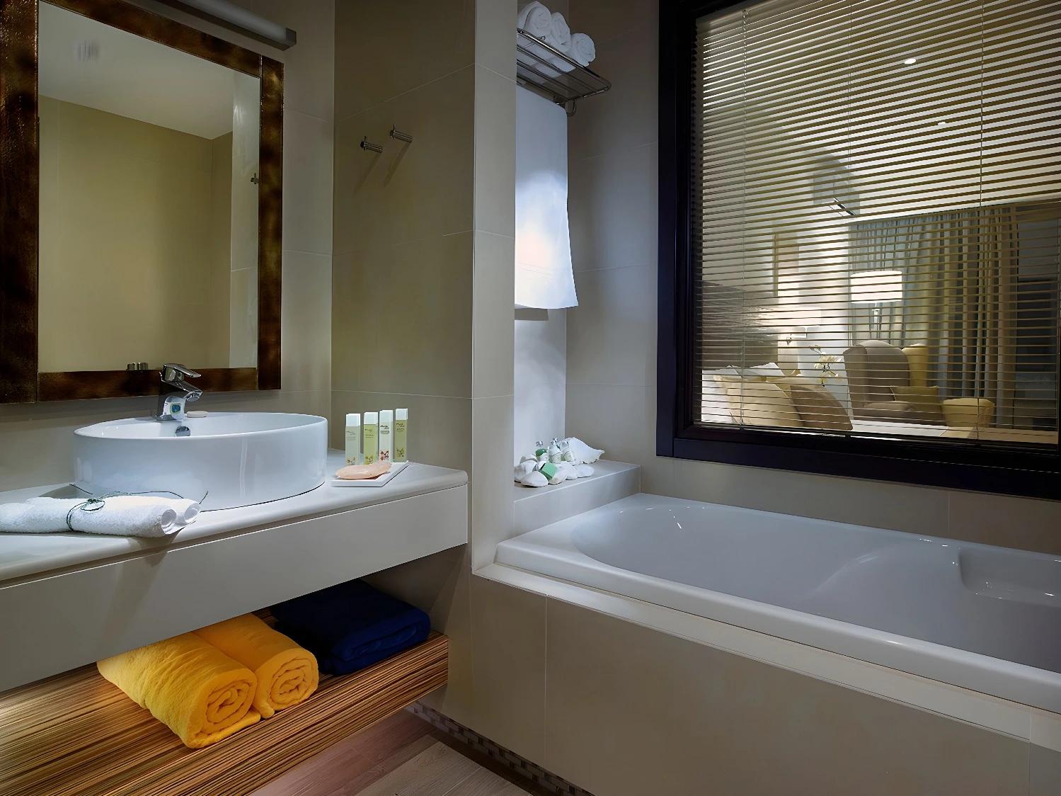 Salle de bain moderne au Filion Suites Resort & Spa avec baignoire et miroir.