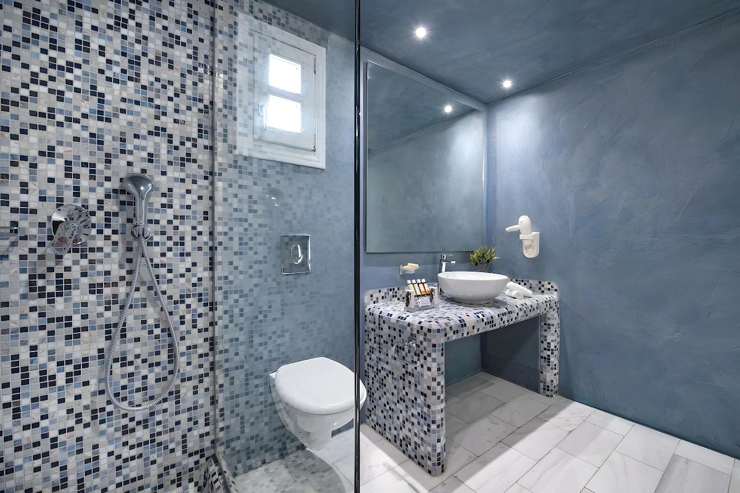 Salle de bain moderne avec douche et lavabo au Santorini Kastelli.