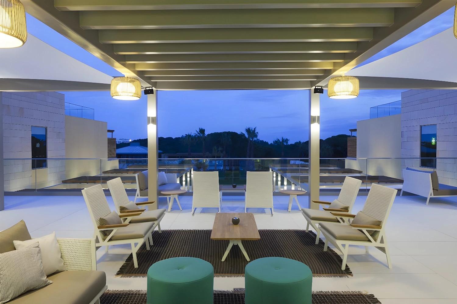 Salon extérieur de l'Epic Sana Algarve avec vue sur le coucher de soleil.