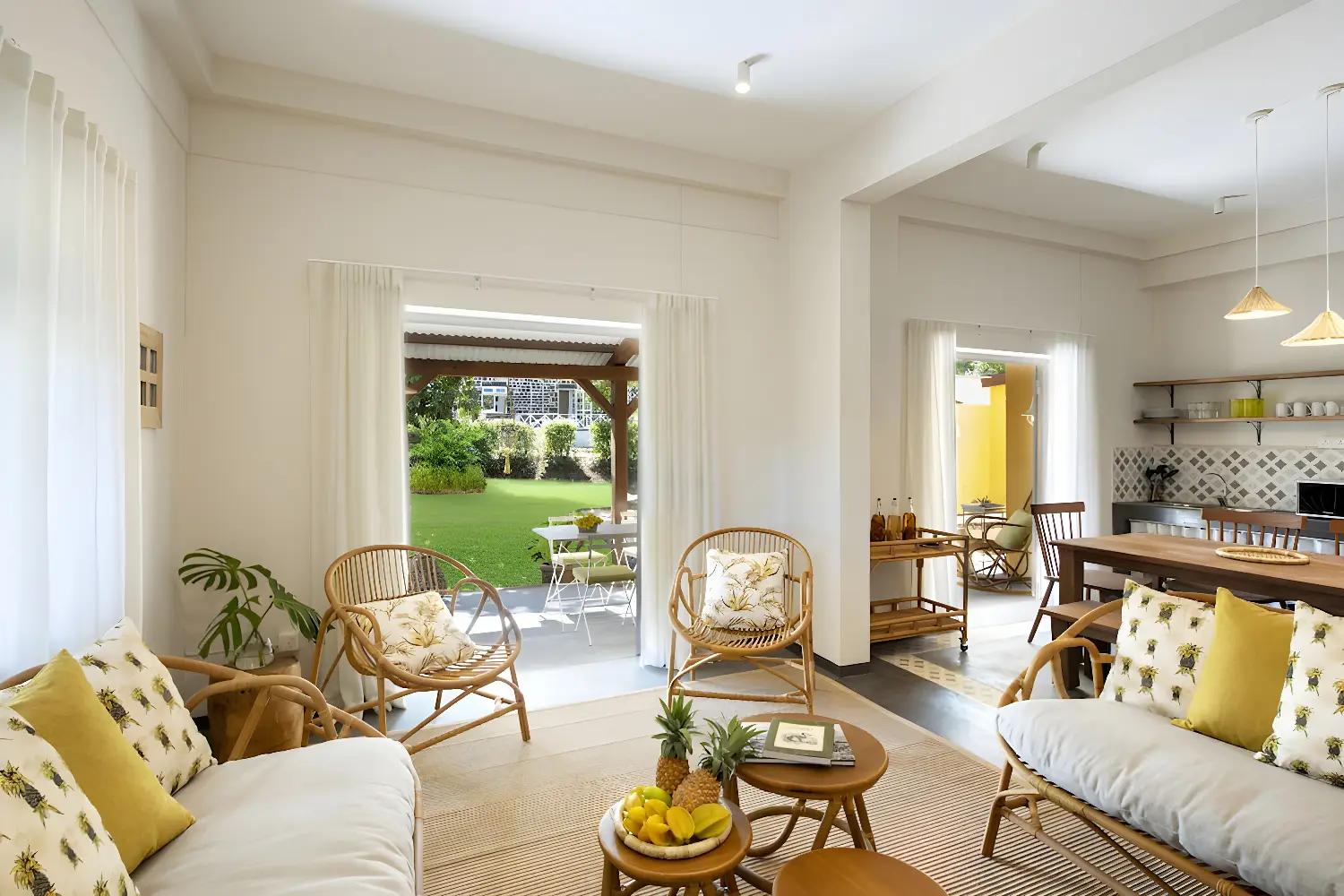 Salon lumineux de Kaz'alala avec mobilier en rotin et vue sur le jardin.