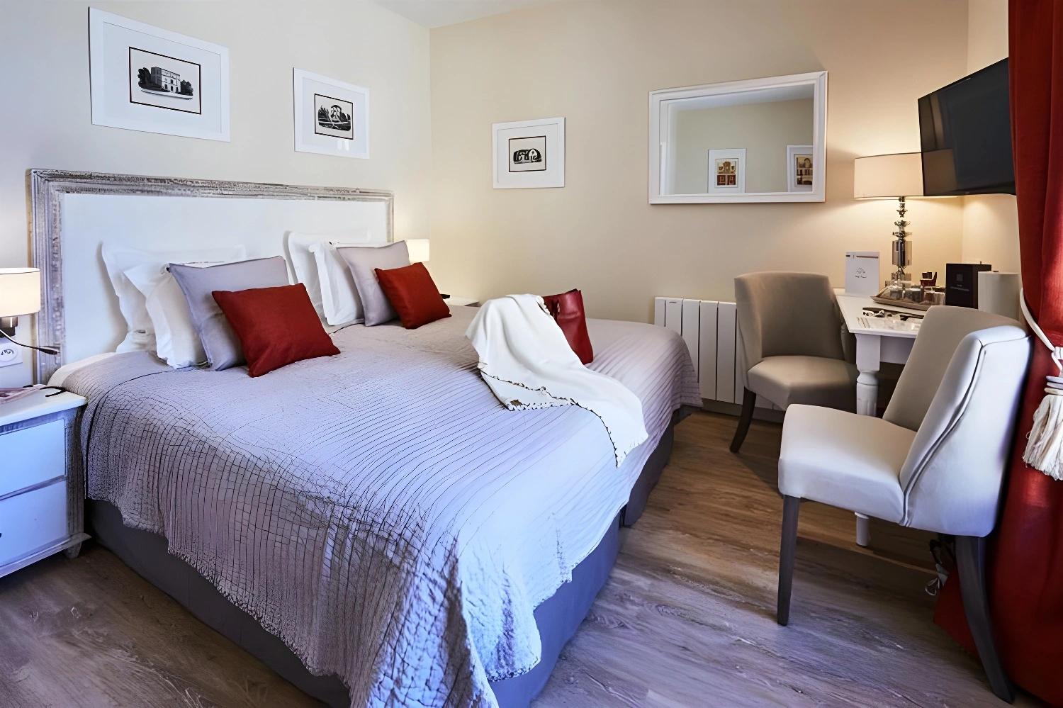 Salon confortable des Villas d'Arromanches avec fauteuils et coussins rouges