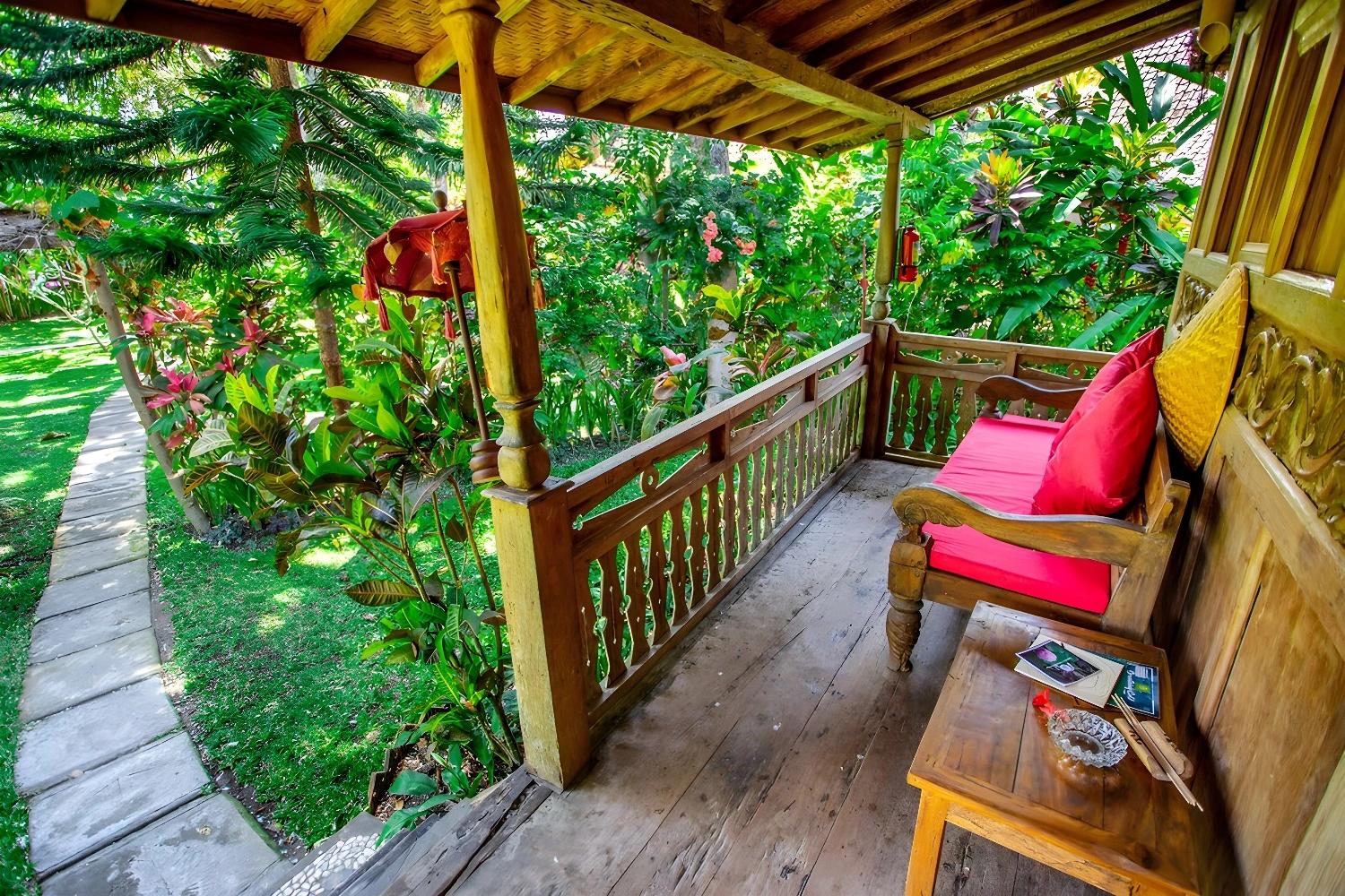 Terrasse en bois du Swasti Eco Cottage avec vue sur le jardin tropical.