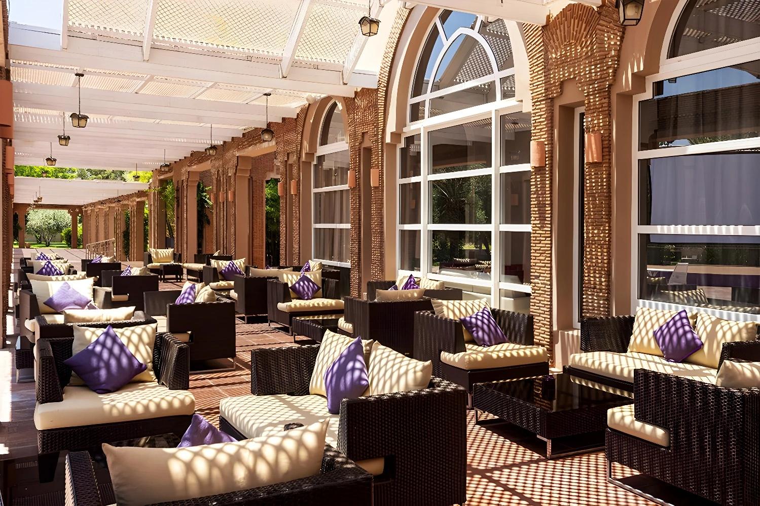 Terrasse confortable de l'Ôclub Zen Barceló Palmeraie avec des sièges en osier et des coussins colorés.