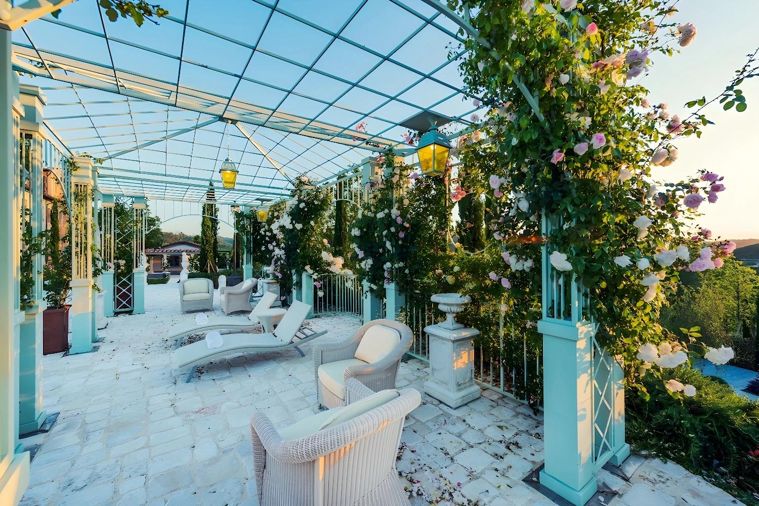 Terrasse fleurie du Relais Sassa al Sole avec des chaises longues sous une pergola.