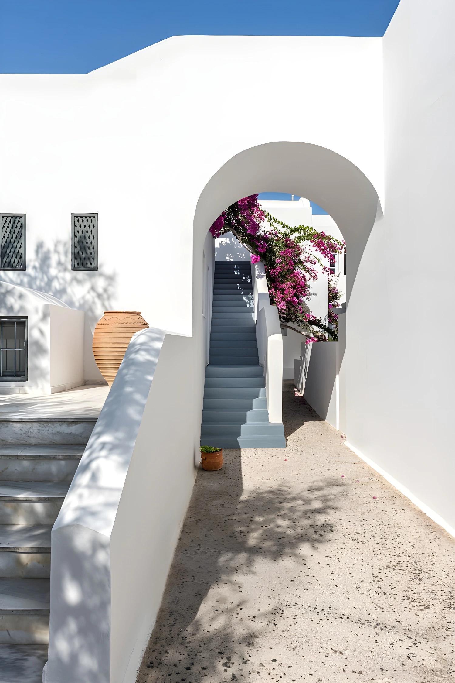 Vue extérieure du Santorini Kastelli avec arc et bougainvilliers.