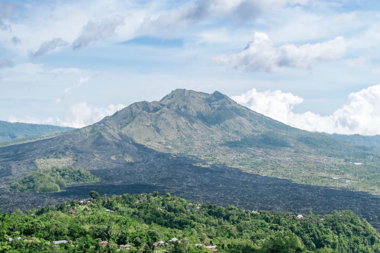 Mont Batur, volcan tranquille entouré de verdure, vue depuis le trekking au lever de soleil.