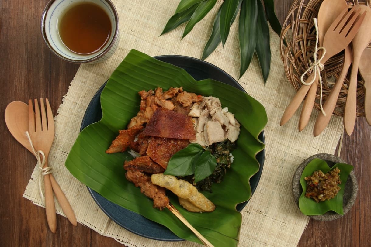 Babi Guling balinais : porc rôti, riz, légumes et sambal, servi dans une assiette en feuilles de bananier.