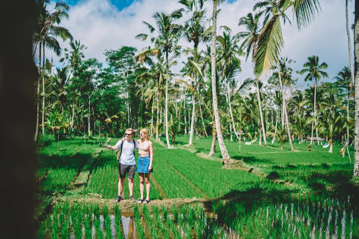 Couple prenant des photos dans un champ de rizières verdoyantes sous un ciel bleu