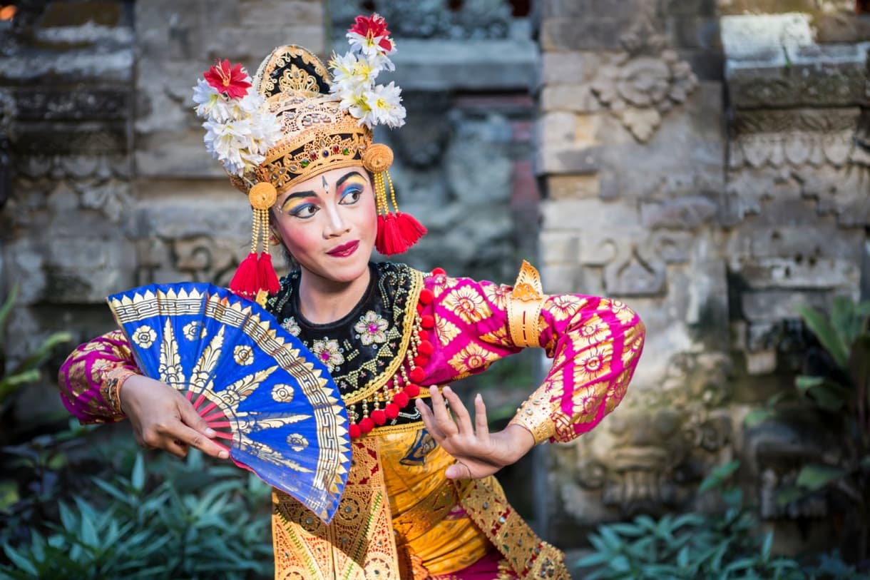 Danseuse traditionnelle balinaise en costume coloré, exécutant une danse au temple de Bali.