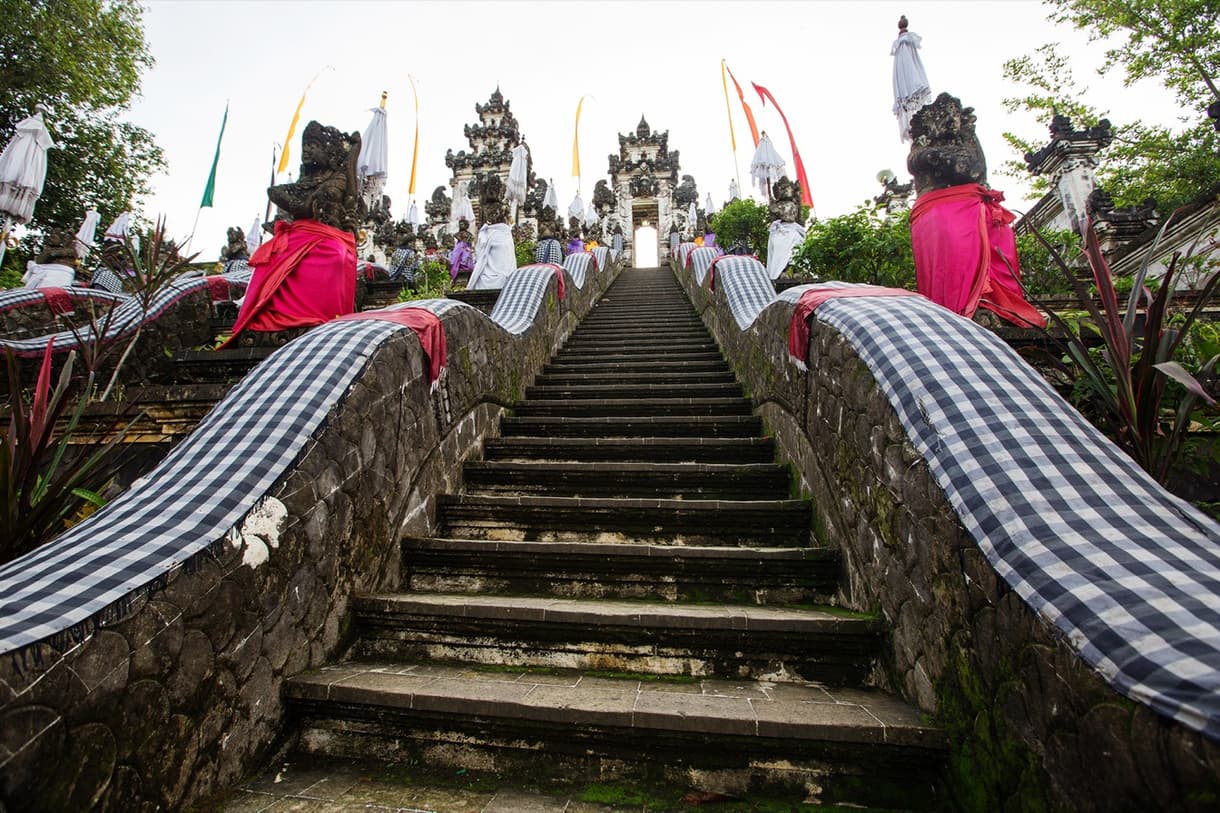 Temple de Lempuyang à Bali, avec des marches menant à des statues et des drapeaux colorés