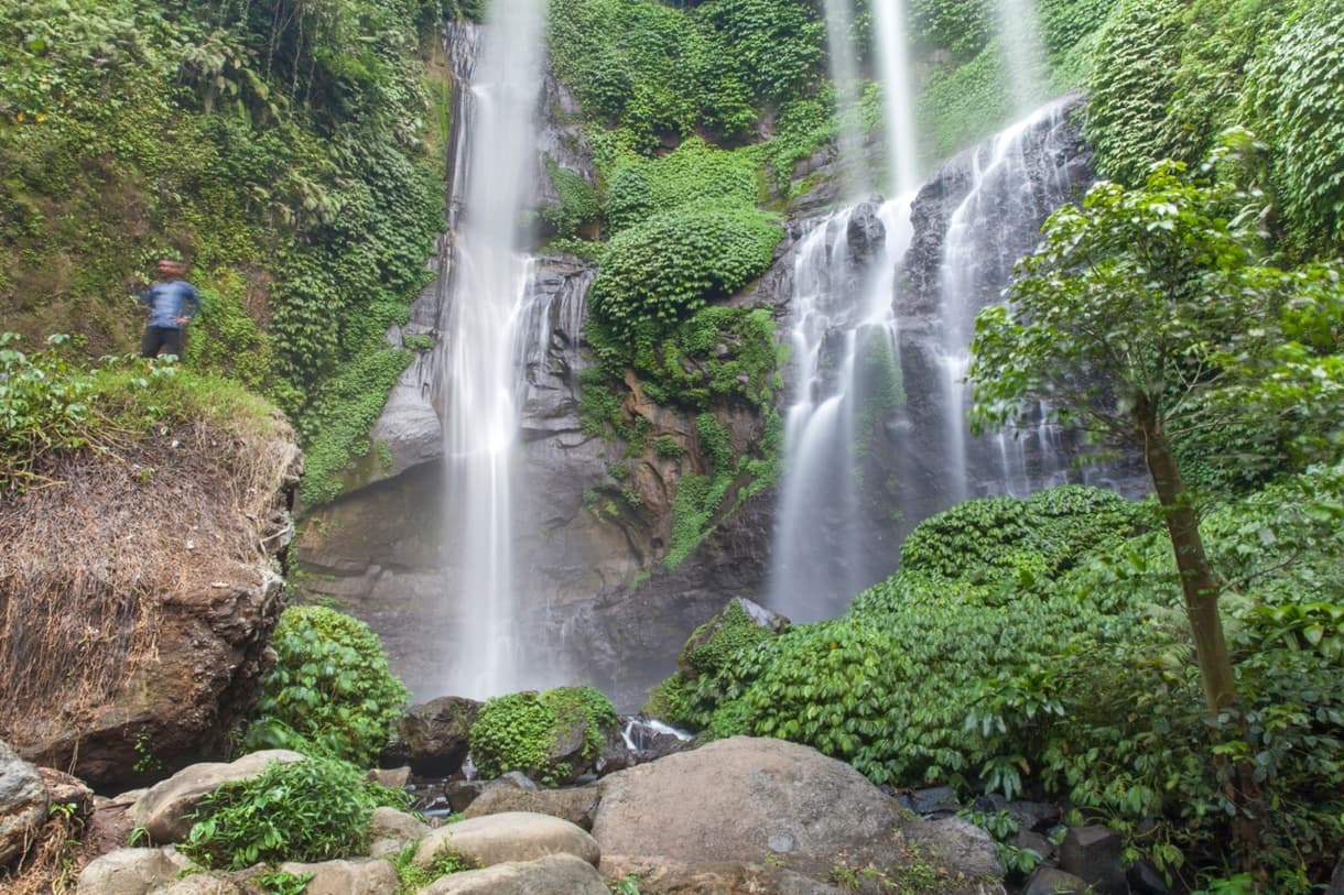 Cascades de Munduk à Bali entourées de verdure luxuriante et d'un randonneur