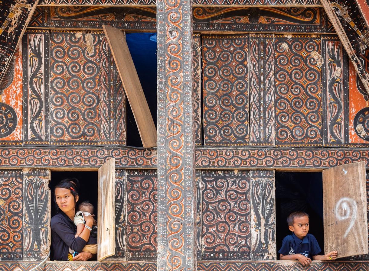 Mère avec un enfant dans un village traditionnel balinais aux motifs colorés