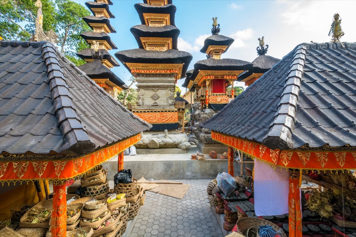 Temple balinais avec toits en chaume et détails colorés, cour intérieure animée
