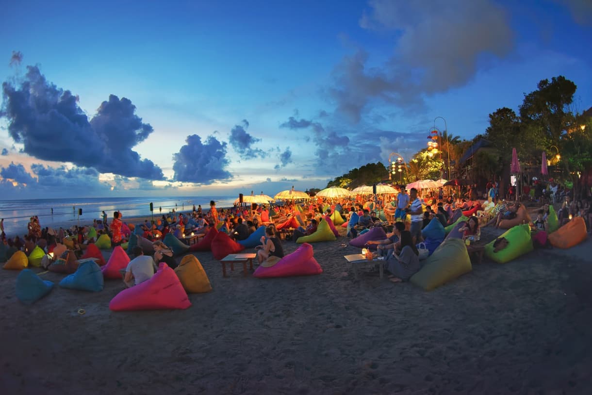 Ambiance animée à Seminyak Beach, avec des transats colorés et des visiteurs profitant du coucher de soleil