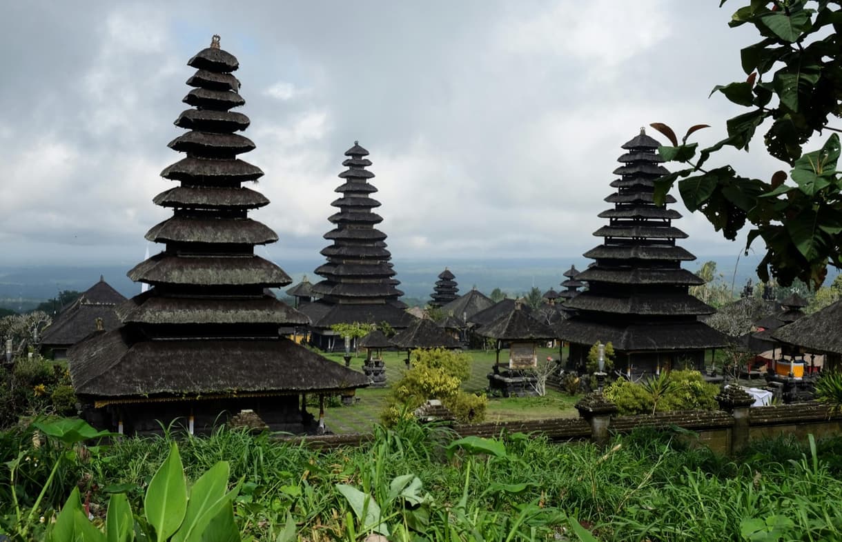 Vue sur des temples balinais avec toits en pagode, entourés de nature verdoyante à Sidemen, Bali.