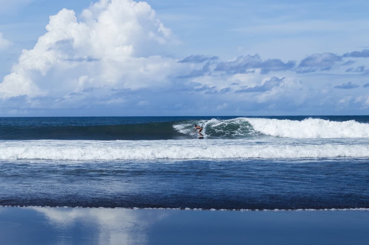 Surf à Bali avec vagues sur un spot de surf, ciel bleu et nuages, ambiance estivale