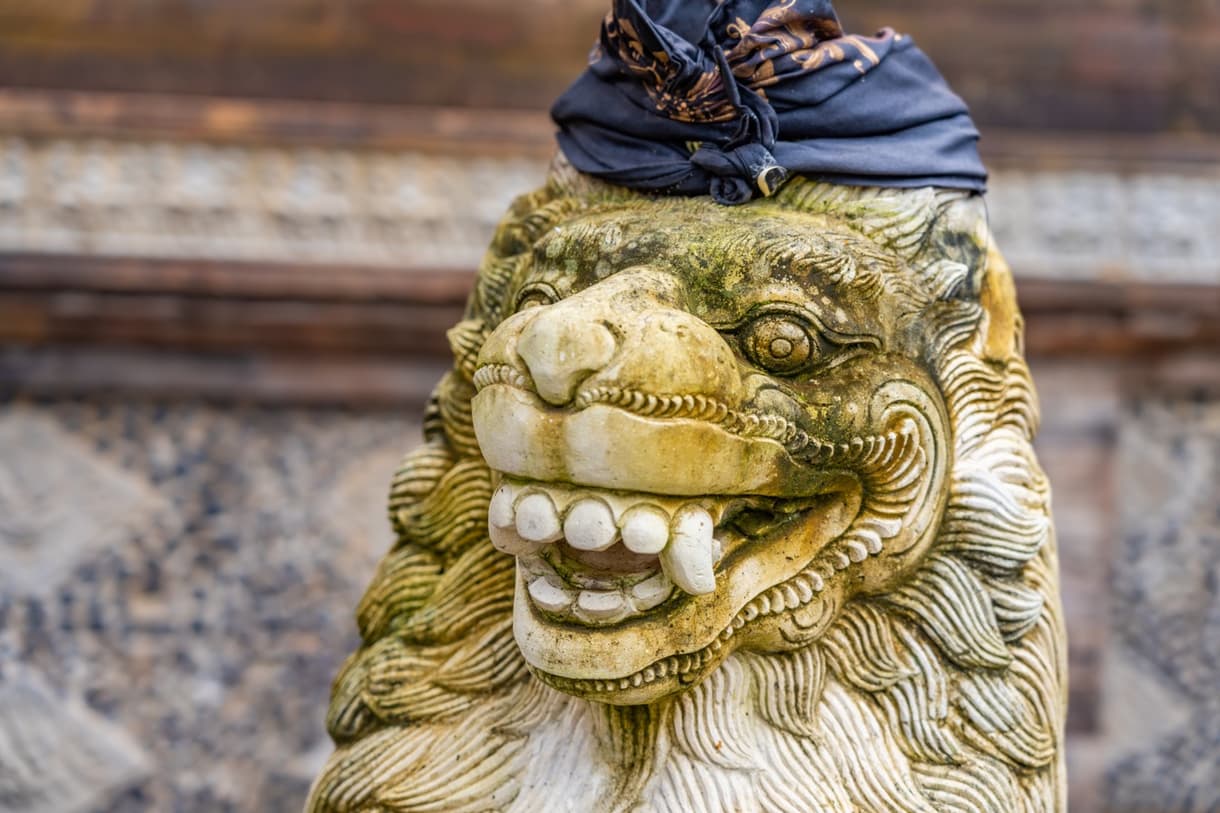 Lion en pierre décoré de noir, symbole balinais, à Tirta Gangga, Bali