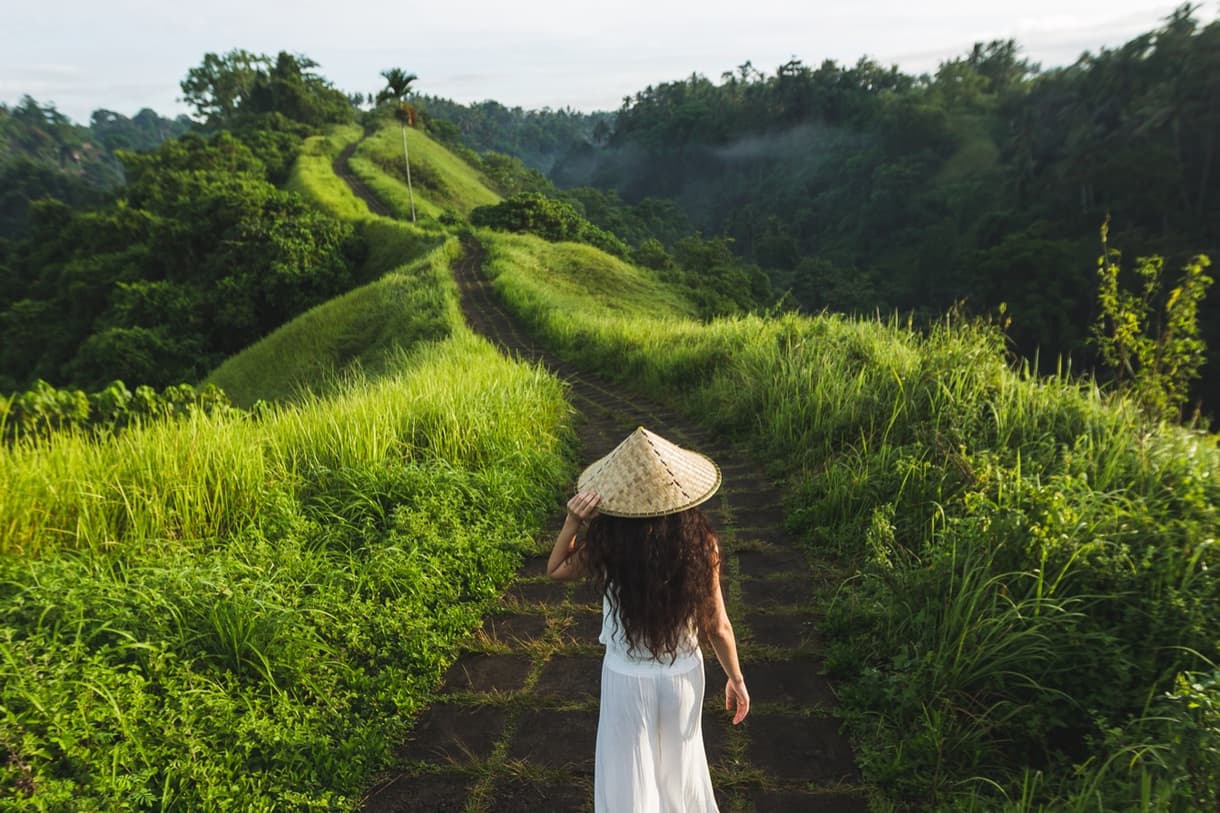 Femme marchant sur un chemin entouré de verdure à Bali