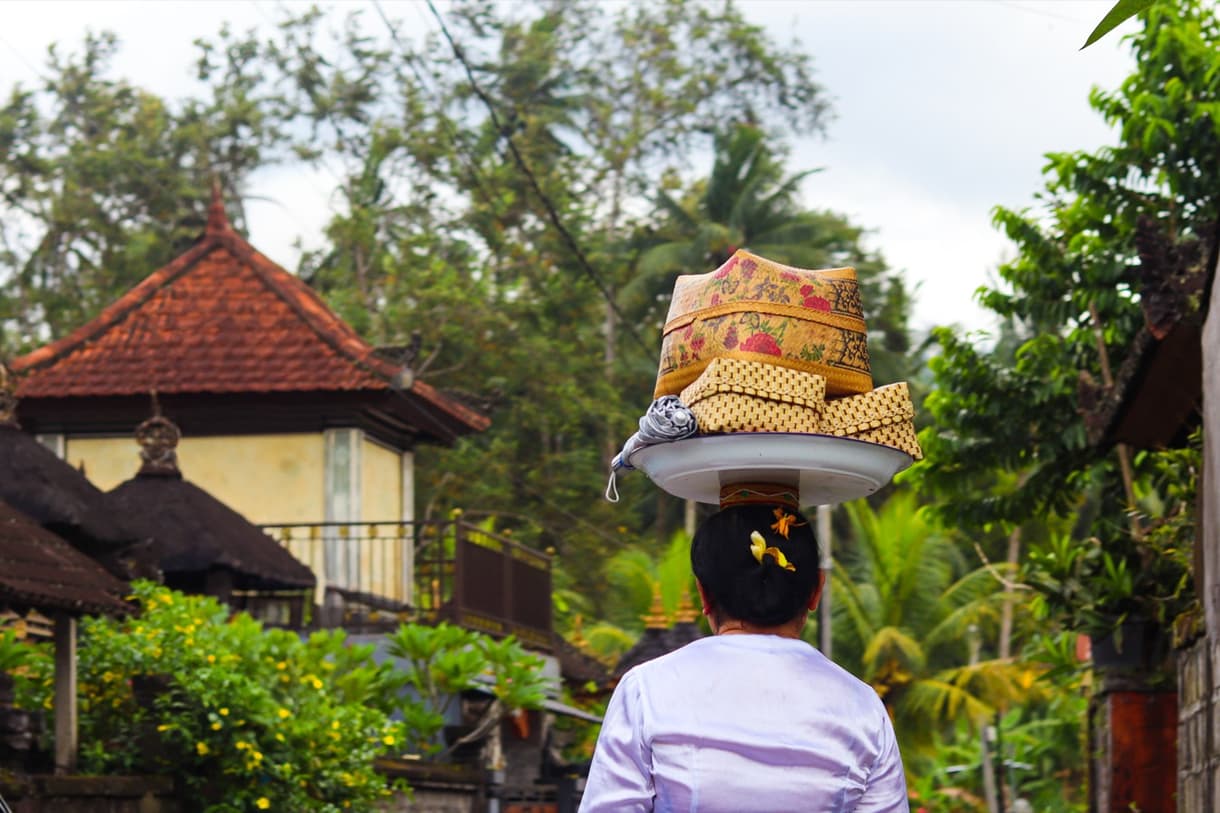 Femme balinaise portant des offrandes sur la tête dans un village traditionnel de Bali