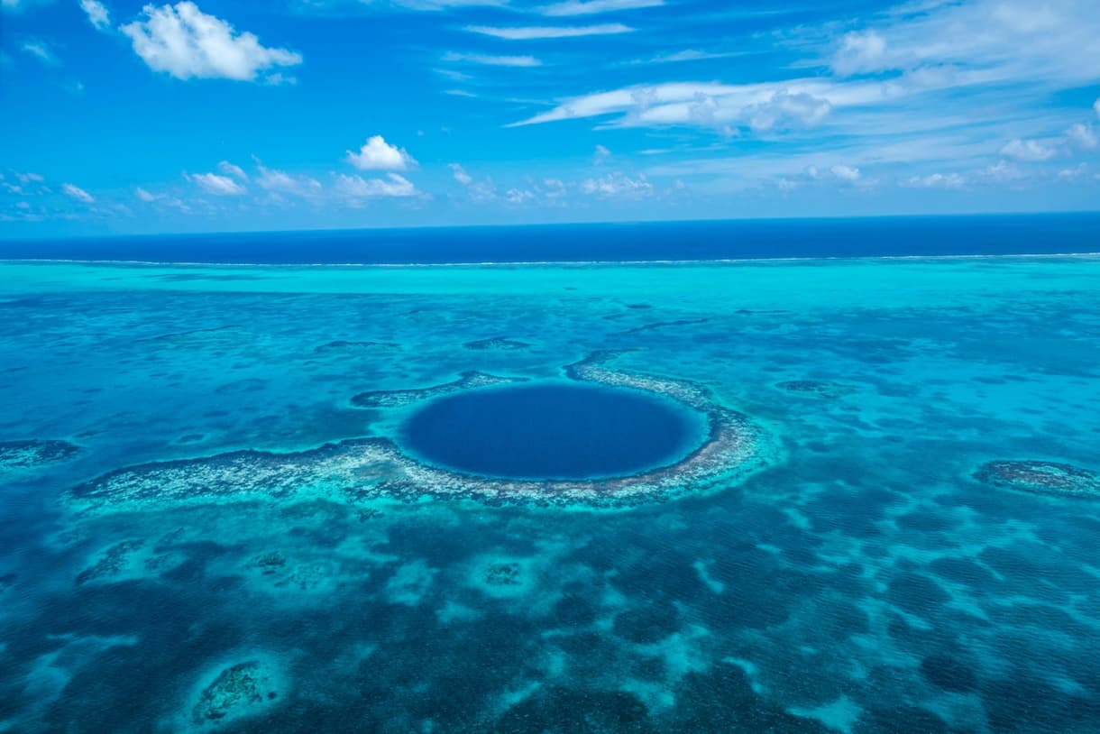 Vue aérienne du Grand Trou Bleu au Belize, un cercle bleu entouré de récifs coralliens dans l'océan turquoise.