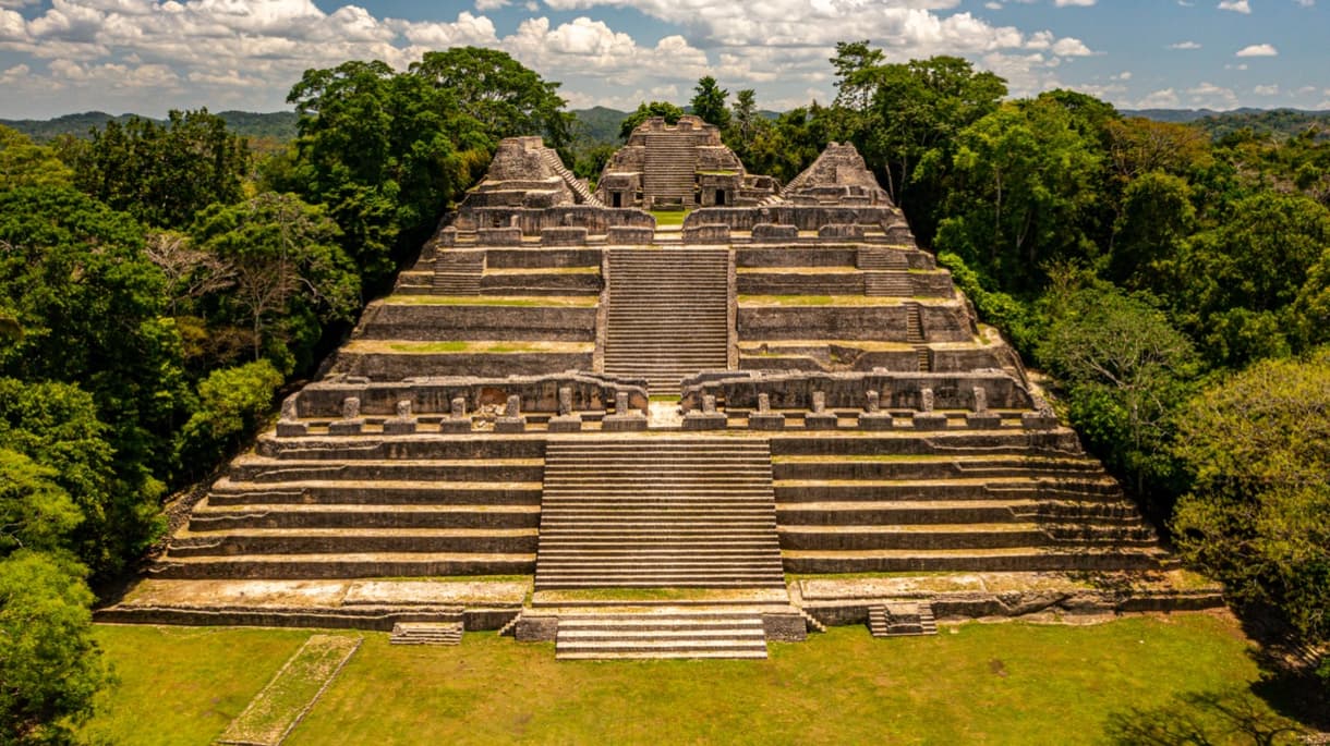 Ruines mayas de Caracol, Belize, avec escaliers et structures en pierre entourés de végétation dense.