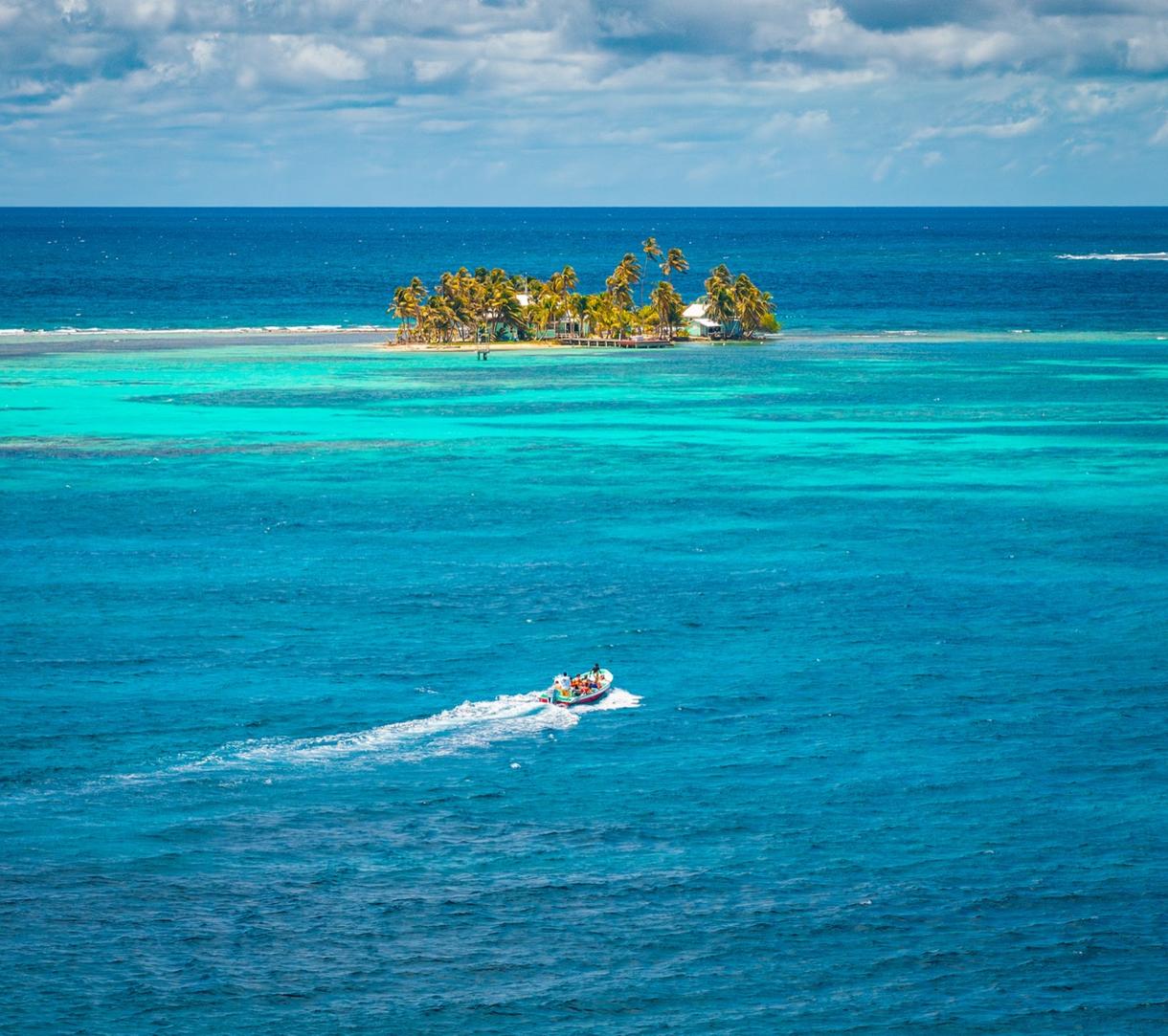 Un bateau à moteur se dirige vers une petite île entourée d'eaux turquoise