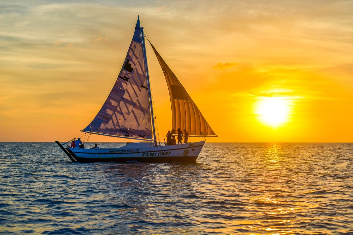 Un bateau à voile naviguant sur l'océan au coucher du soleil