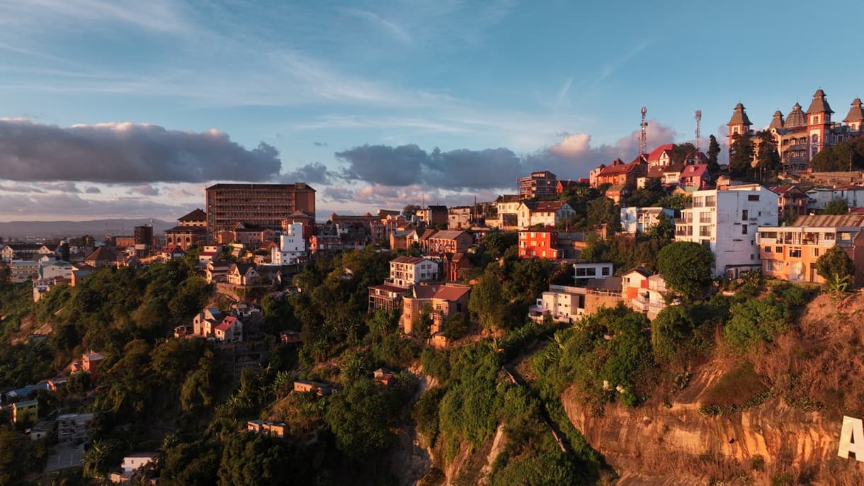 Antananarivo au coucher du soleil, présentant ses maisons colorées et collines verdoyantes.