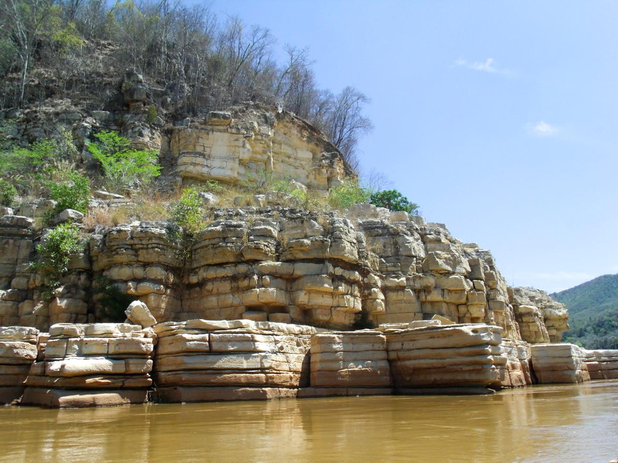 Bord du fleuve Tsiribihina, rochers et végétation verdoyante sous un ciel bleu