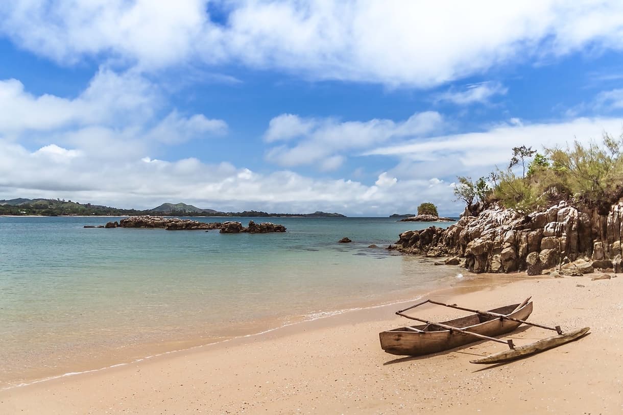 Plage de Nosy Sakatia avec une barque en bois et une mer turquoise sous un ciel bleu