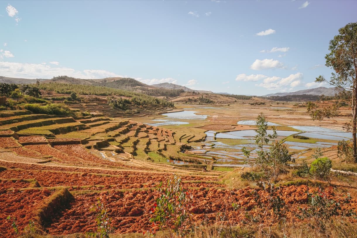 Paysage rural de Madagascar avec rizières en terrasses et lacs, sous un ciel bleu