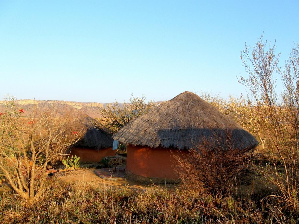 Huttes traditionnelles au lever du soleil, entourées de végétation, à Madagascar.