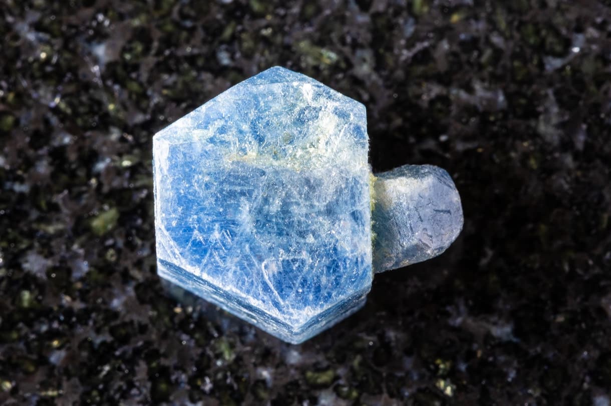 Cristal de saphir bleu brut sur fond noir, mettant en valeur sa couleur et sa transparence