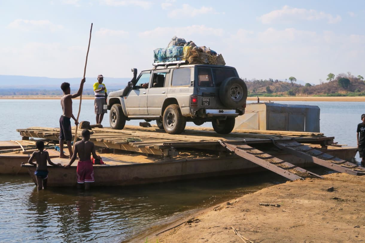 4x4 sur un bac le long de la piste côtière, avec des hommes et des enfants dans l'eau