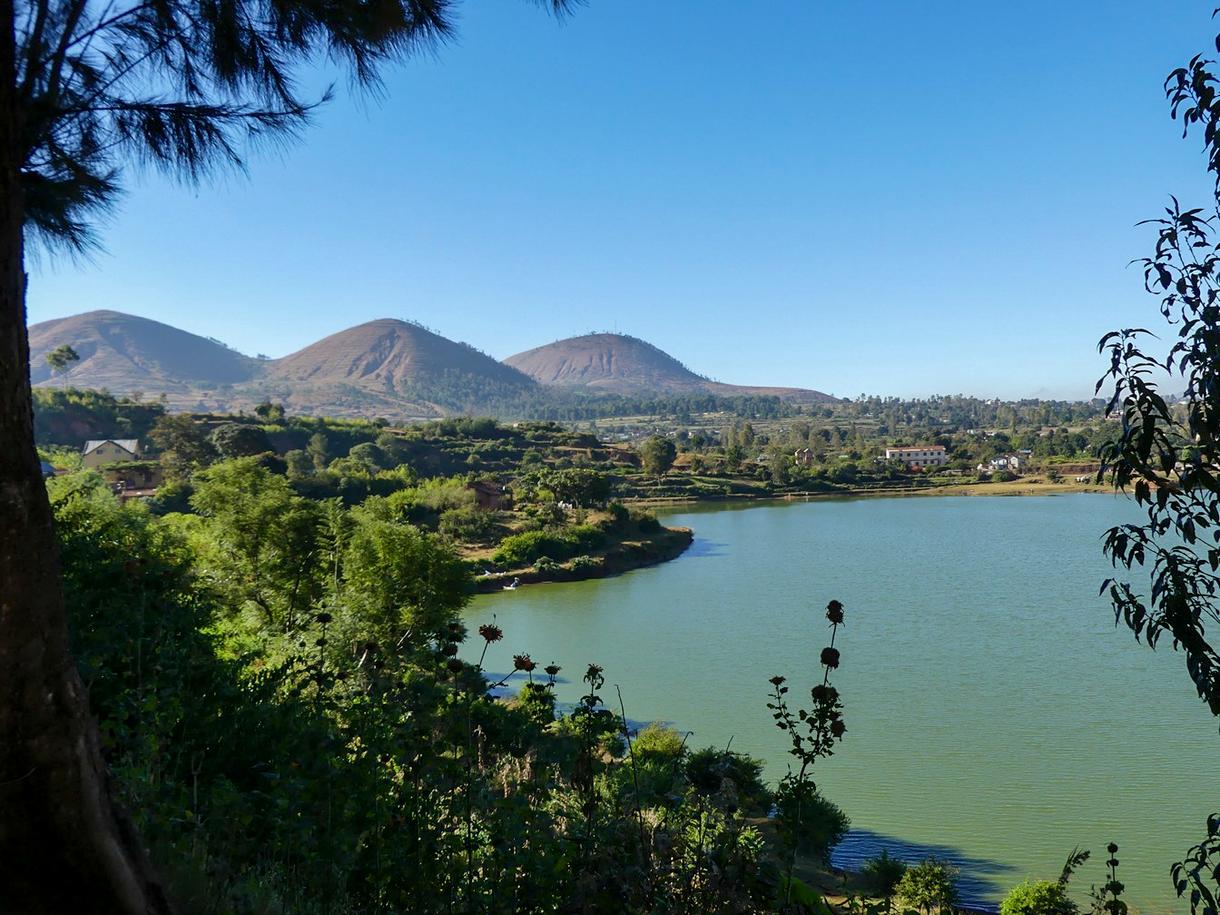 Lac entouré de collines verdoyantes à Madagascar sous un ciel clair